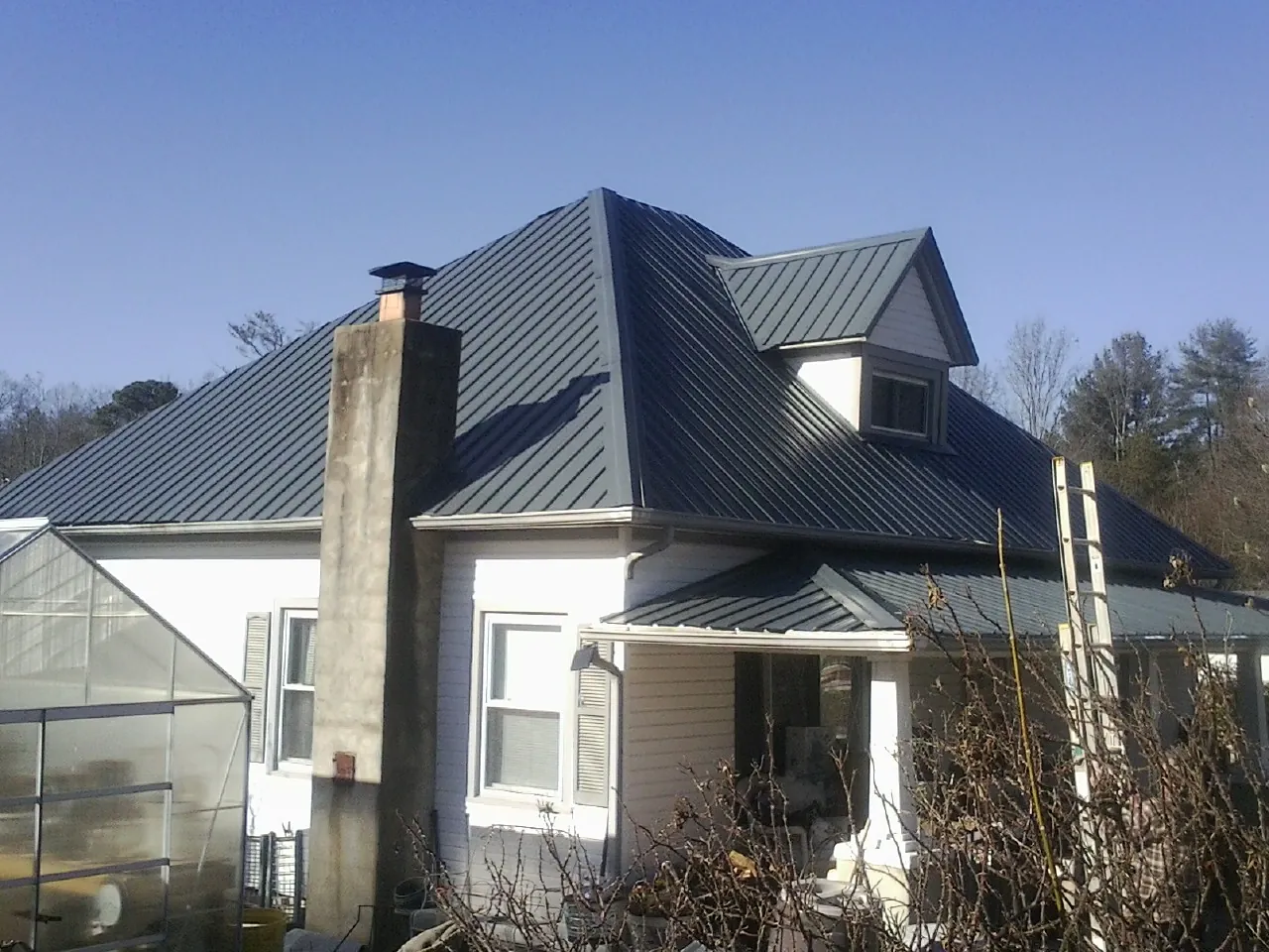 Dark blue standing seam metal roof on a white farmhouse with dormer — Slate & Tile Roof Repair by Roofing Brothers in Mazon