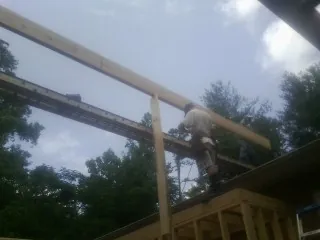 Carpenter setting a ridge beam over a new addition frame — Ice Dam Removal by Roofing Brothers in Mazon