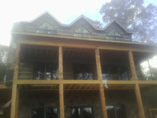Dormers and porch framing on a large log home under construction — Roof Coating work by our crew in Mazon
