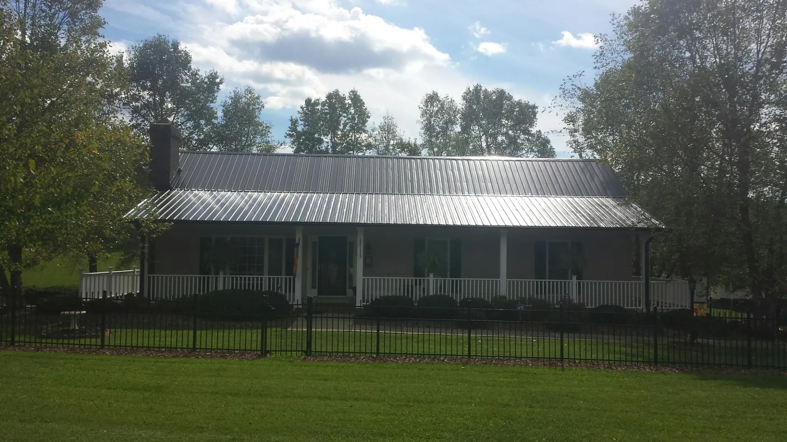 Gray metal roof on a brick ranch with a full width front porch — Gutter Guard Installation work by our crew in Mazon