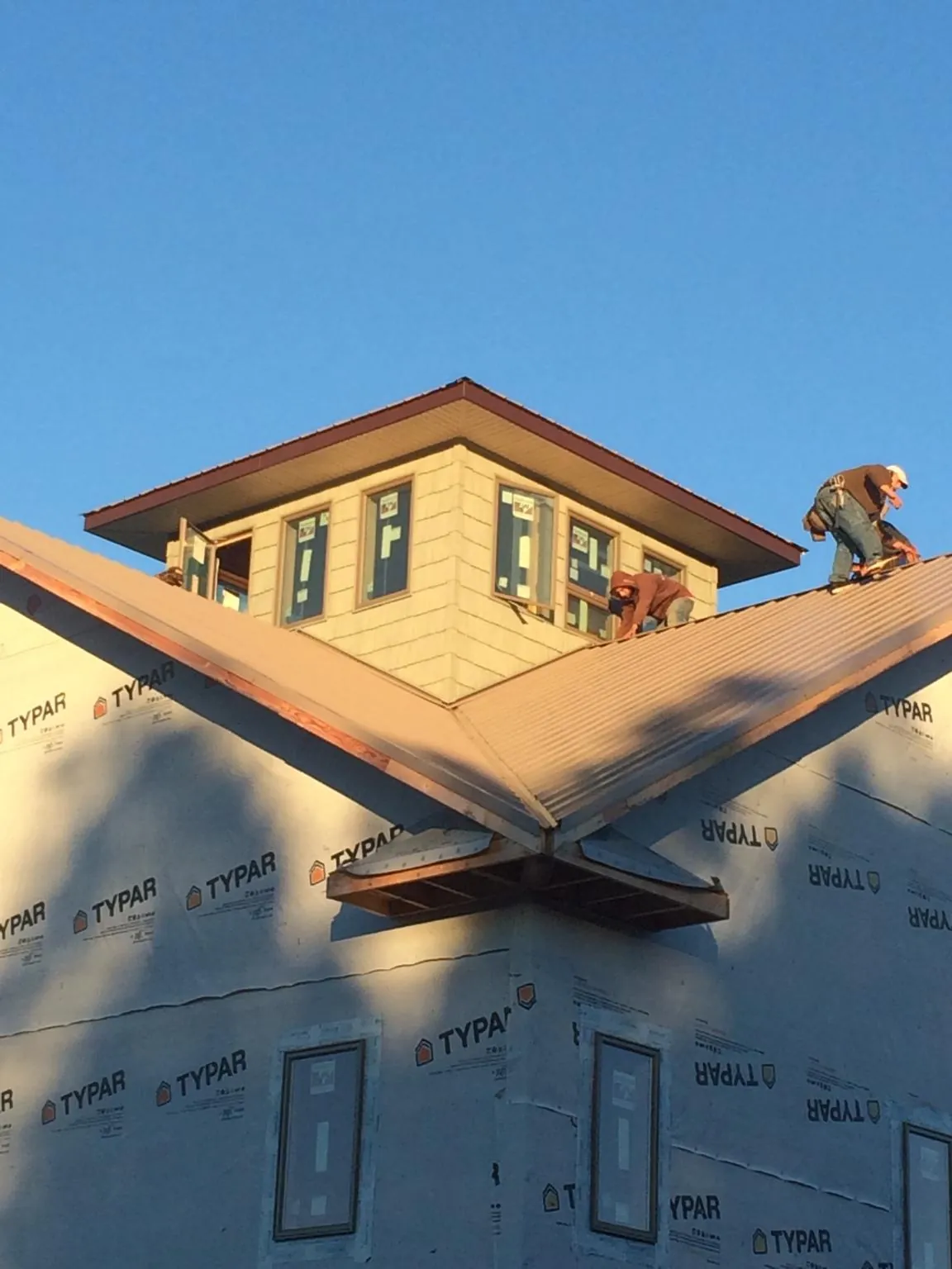 Roofers working around a rooftop cupola on a new metal roof at sunset — Roof Waterproofing in Mazon by Roofing Brothers